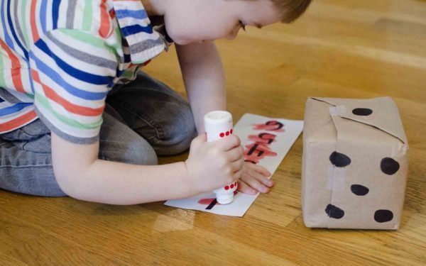 boy crossing out numbers during the roll and cross dice game 