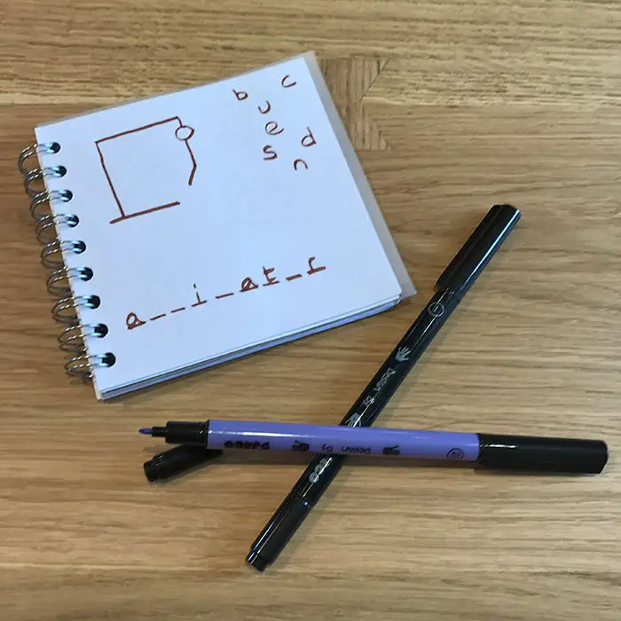 two pens and a paper with Hangman